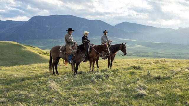 Ranch landscape in the Bighorn Mountain foothills with riders on horseback